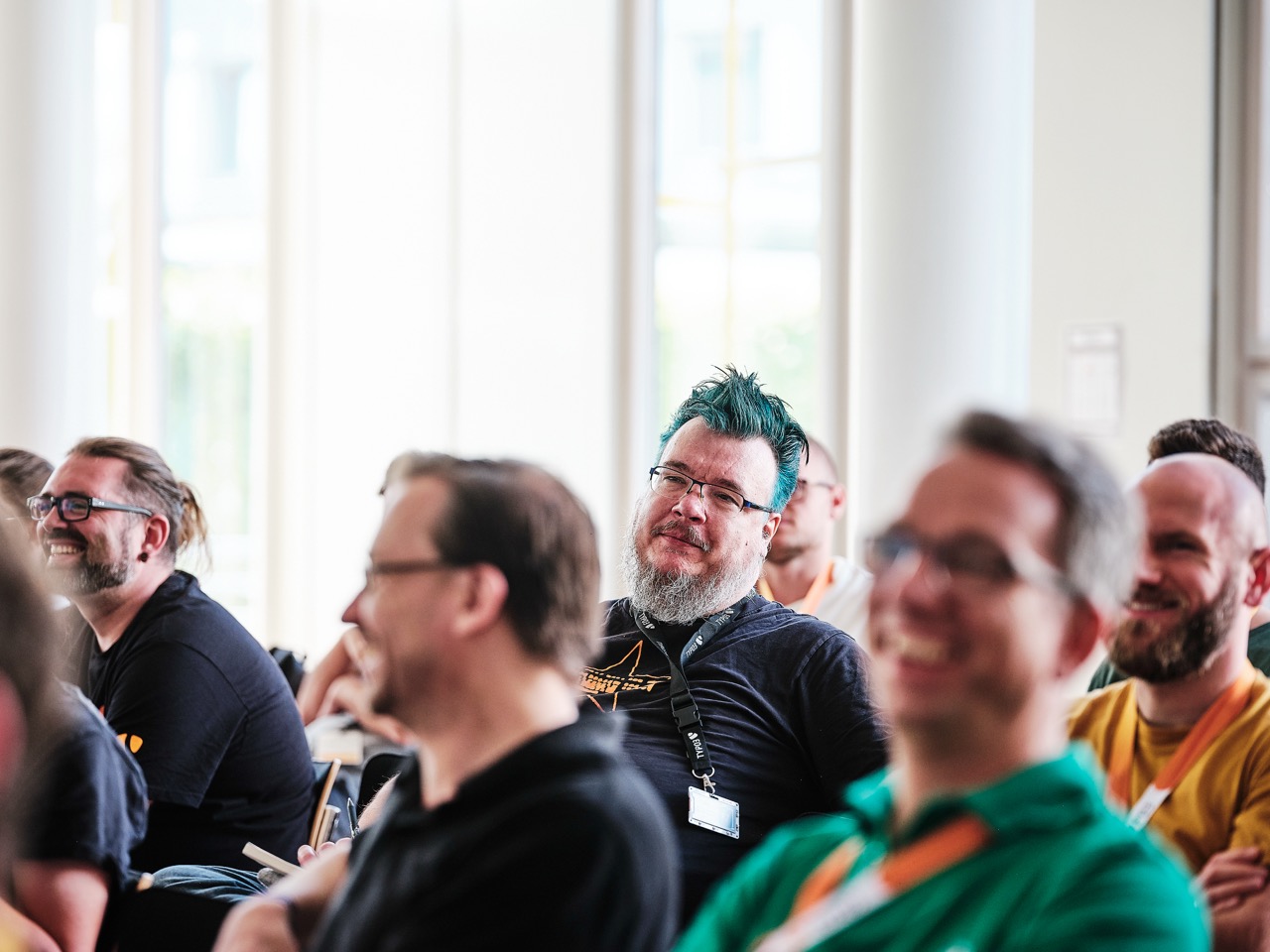 Several people seated in the audience listening attentively.